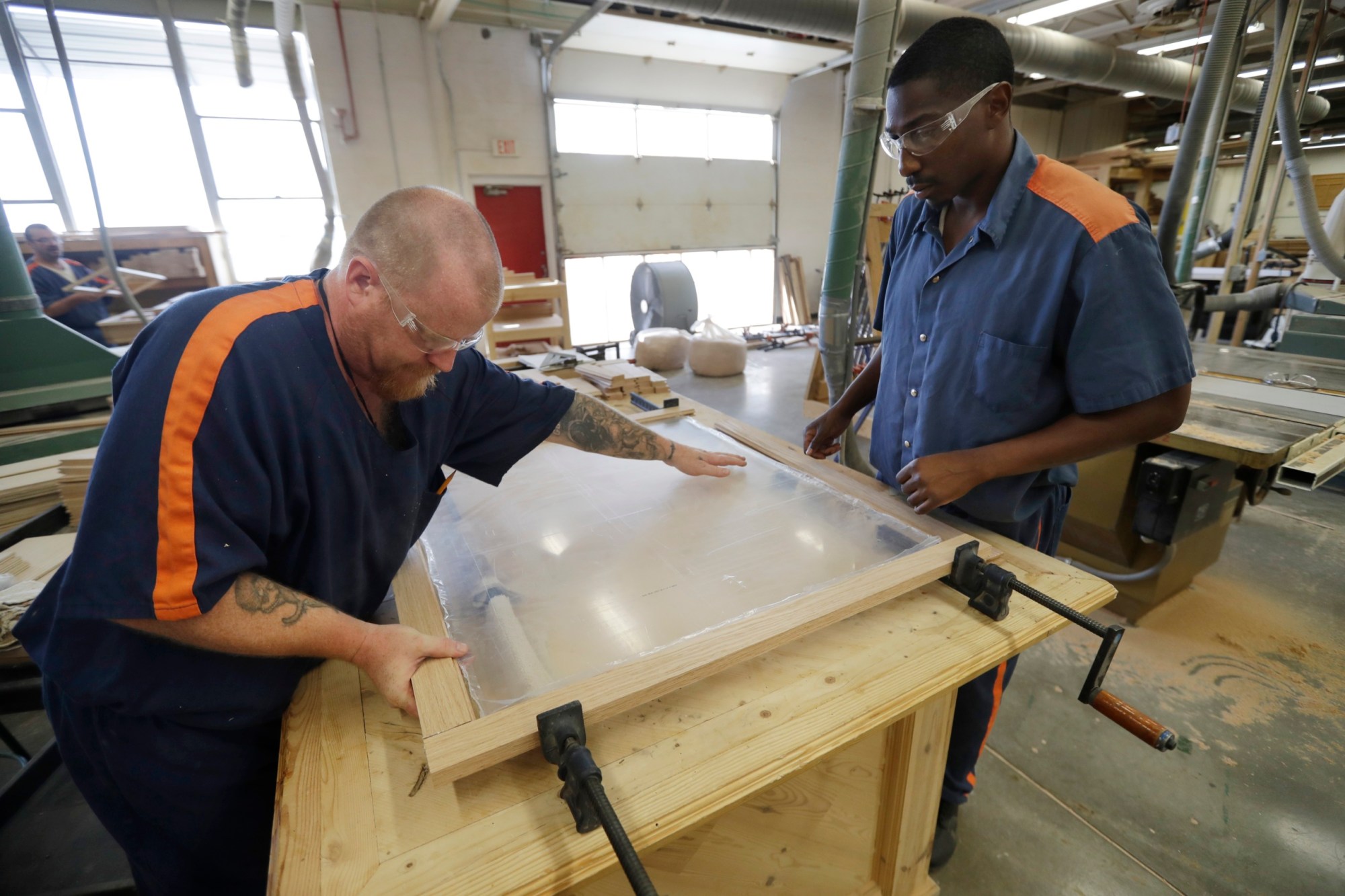 In a photo from Friday, July 8, 2016, inmates James Fletcher, left, and DeAndre Allen work on cabinet doors at the Habitat for Humanity Prison Build at the Ionia Correctional Facility in Ionia, Mich. Few states have been more aggressive in releasing inmates and diverting offenders than Michigan, where the prison system has long threatened the state???s capacity to fund universities and other basics of government. But the $2 billion annual cost remains steep, exacerbated by a boomerang found here and across the country: the large number of inmates who wind up back behind bars again. Now Michigan leaders, frustrated that their downsizing efforts have hit a wall, are trying novel, more hands-on methods to ensure that prisoners leave with a job in hand. (AP Photo/Carlos Osorio)