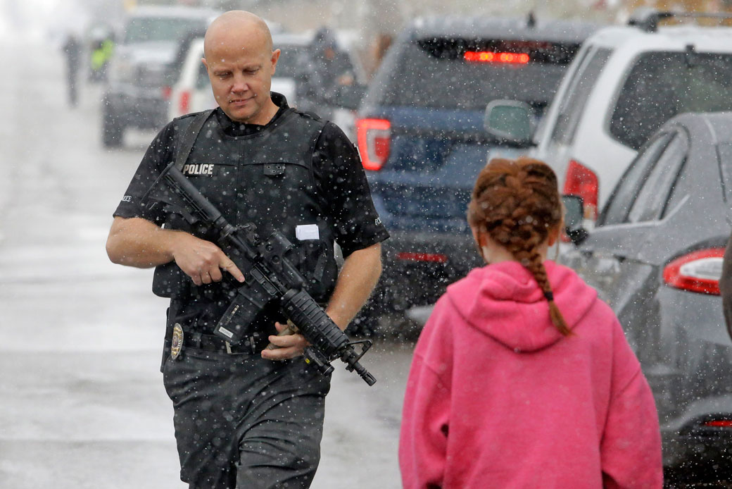 A police officer carries his weapon in front of Mueller Park Junior High after a student fired a gun into the ceiling in Bountiful, Utah in December 2016. (AP/Rick Bowmer, File)