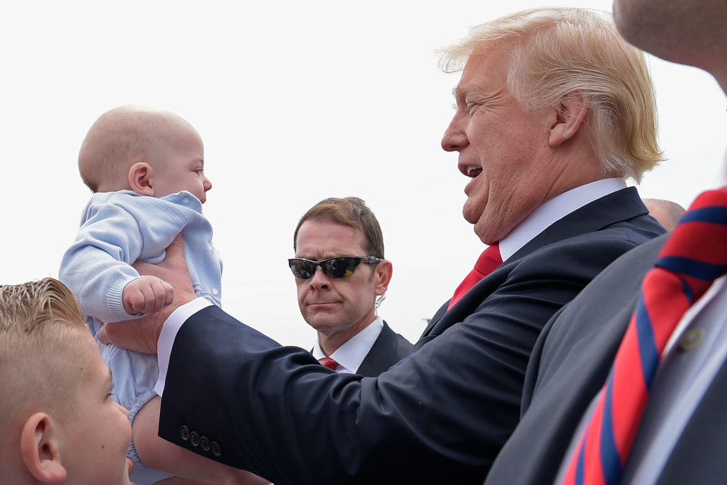 President Donald Trump picks up a baby as he greets people after arriving on Air Force One at General Mitchell International Airport in Milwaukee, April 2017. (AP/Susan Walsh)