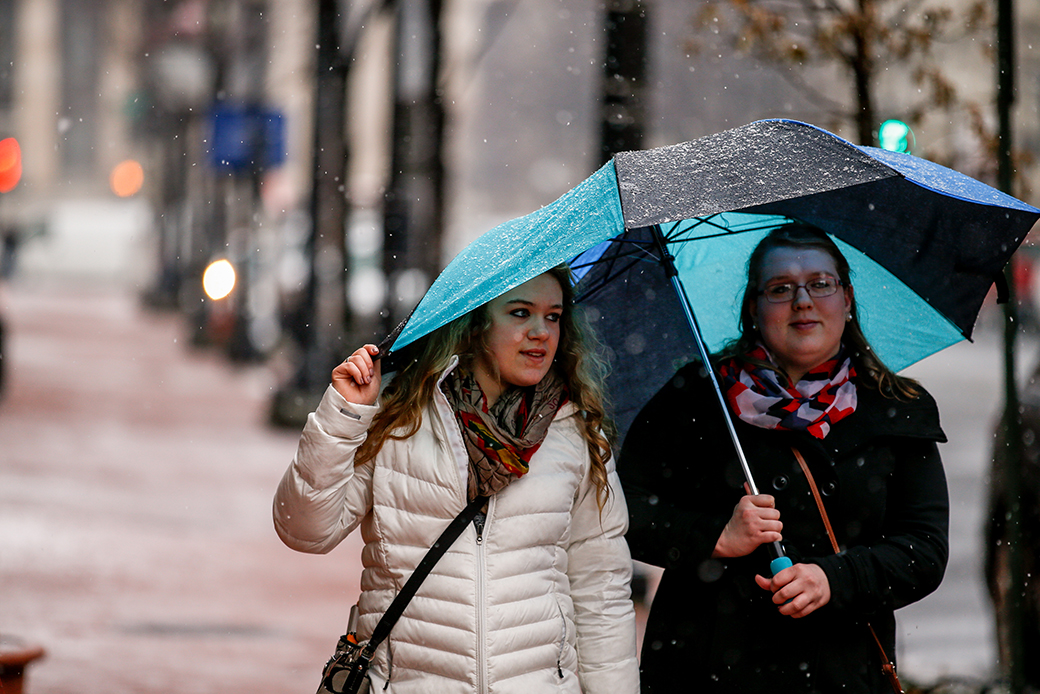Two women share an umbrella in Washington, March 5, 2015, as snow begins to fall. (AP/Andrew Harnik)