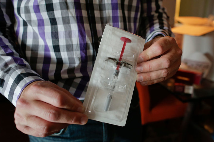 Brian Greenberg, who suffers from Crohn’s disease, holds up a syringe preloaded with his prescription medication that was delivered to his home in Stamford, Connecticut, July 6, 2016. (AP/Julie Jacobson)