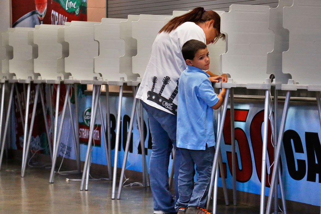 A woman completes her ballot as a child waits in Pueblo, Colorado, on September 10, 2013. (AP/Brennan Linsley)