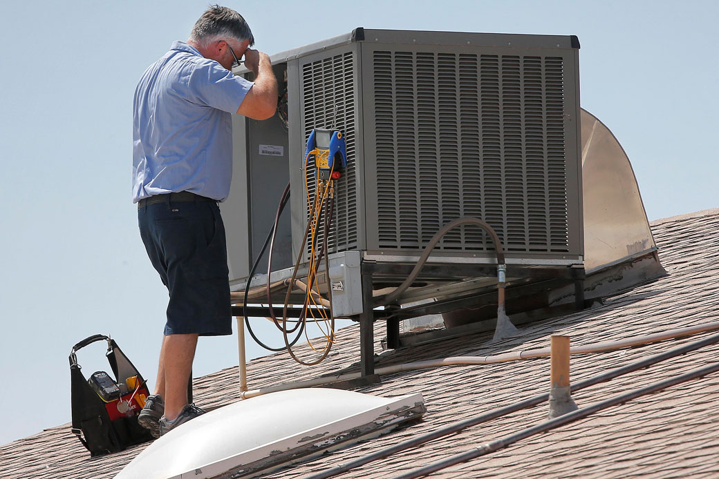 Parker & Sons Air Conditioning warranty supervisor Michael Hawks wipes his brow while inspecting an a/c unit, June 28, 2013, in Phoenix. (AP/Matt York)