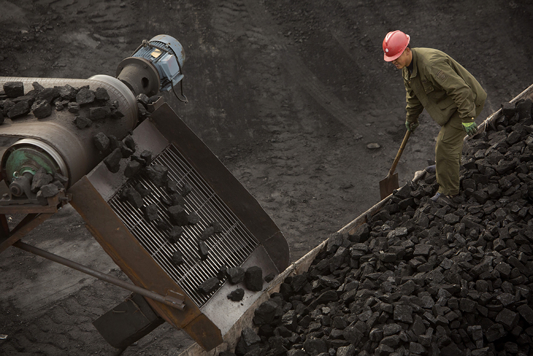 A worker watches as a conveyor loads coal onto a trailer truck at a coal mine near Ordos in northern China's Inner Mongolia Autonomous Region, November 2015. (AP/Mark Schiefelbein)