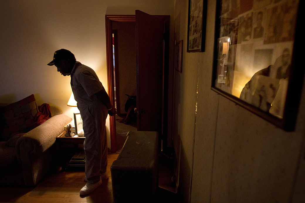 A man stands next to family photos in his home, February 2011.