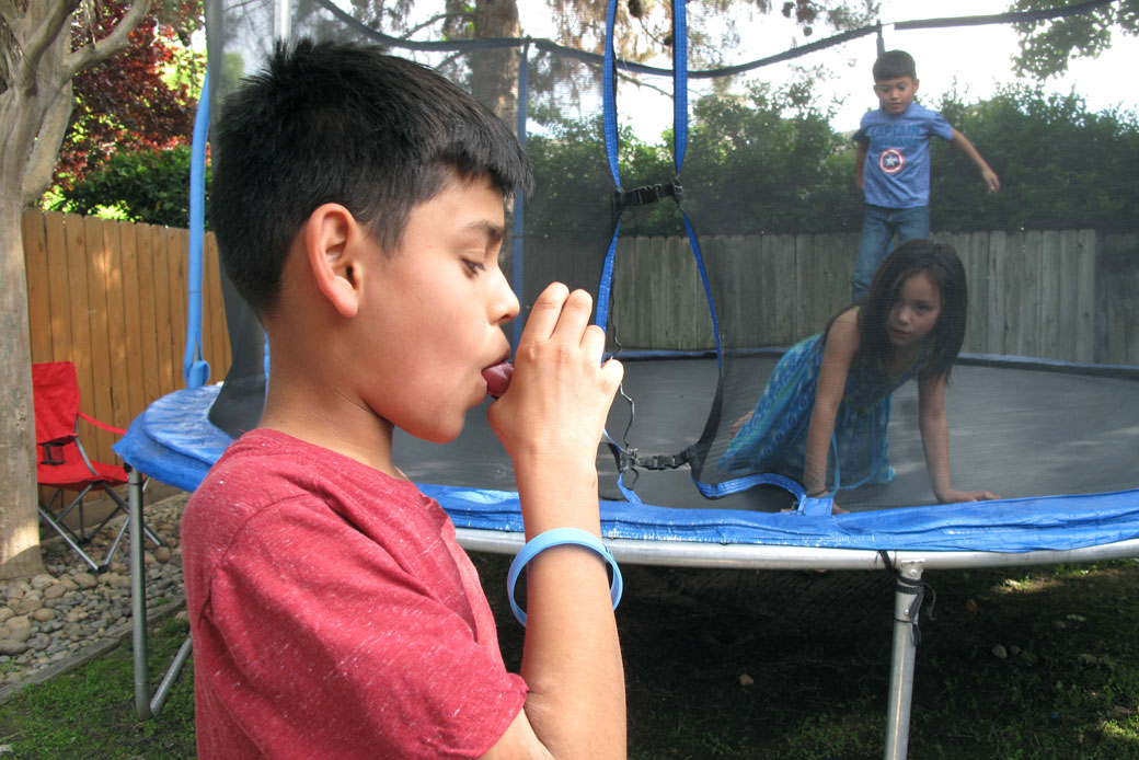 A boy in Fresno, California, demonstrates how he uses an inhaler to combat asthma, made worse by air pollution in San Joaquin Valley, April 2017. (AP/Scott Smith)