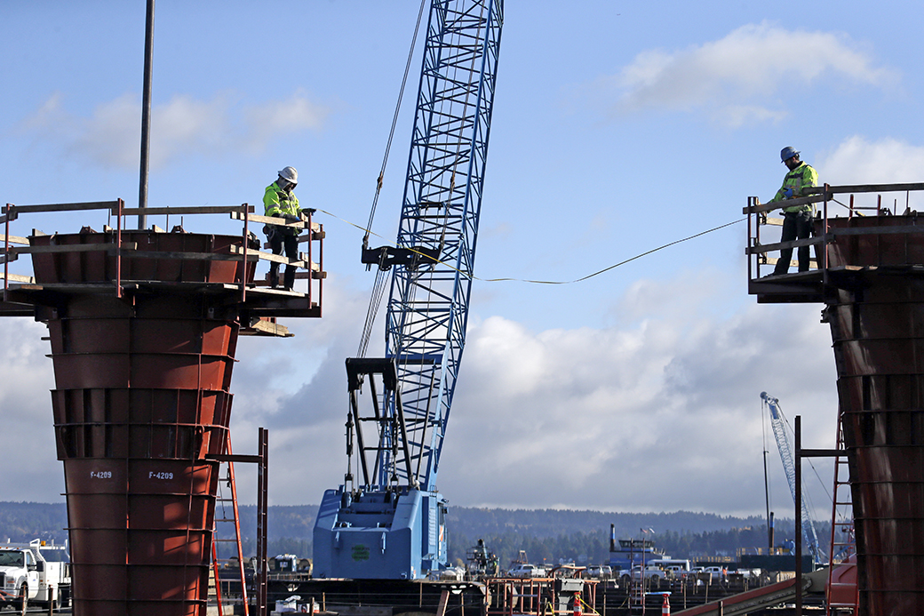 Workers take a measurement across new solid concrete bridge columns under construction on the new State Route 520 floating bridge across Lake Washington, November 2015, in Seattle. (AP/Elaine Thompson)