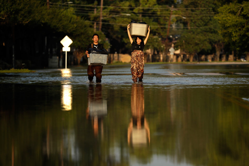 Mariko Shimmi, right, helps carry items out of Ken Tani's home in a neighborhood still flooded from Harvey on Monday, September 4, 2017, in Houston. (AP/Gregory Bull)