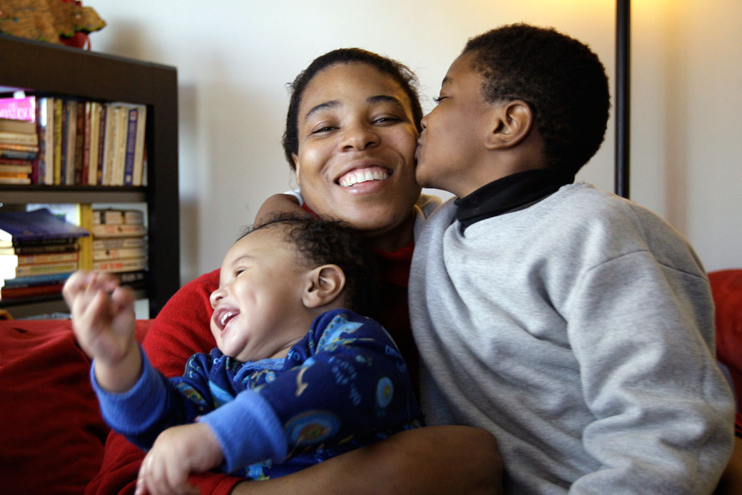 A Jamaican immigrant mother embraces her children in their apartment in Seattle, November 24, 2008. (AP/Elaine Thompson)