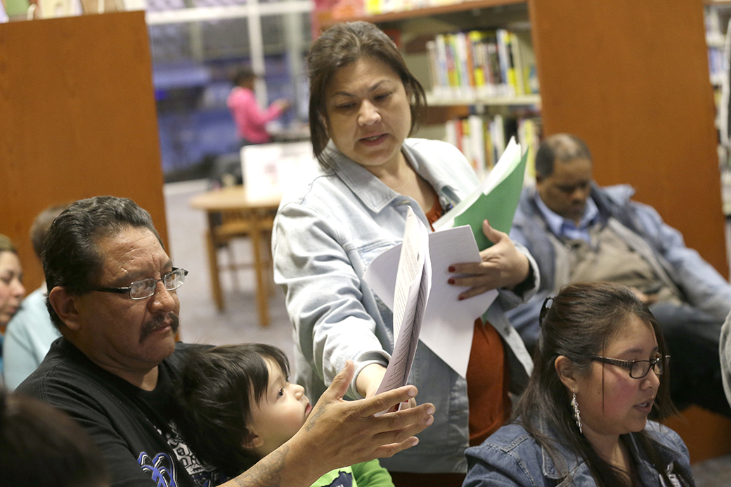 A health network patient navigator, center, helps a man with documents during an Affordable Care Act enrollment event at a library in Texas, February 2015. (AP/LM Otero)