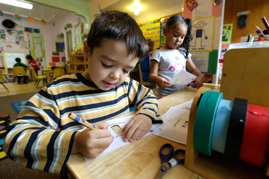 Children work with scissors and colored pencils at a desk, October 2014. (AP/Ted S. Warren)