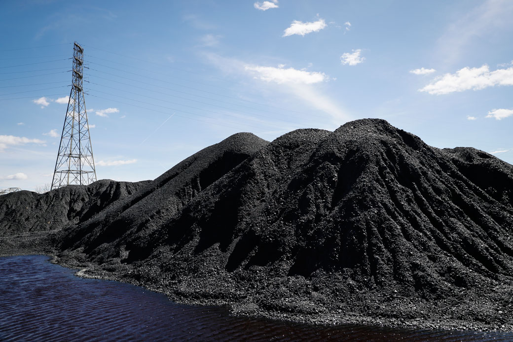 Piles of coal rest at a facility along the Ohio River in Cincinnati, Ohio, as power transmission lines stand in the background, April 7, 2017. (AP/John Minchillo)