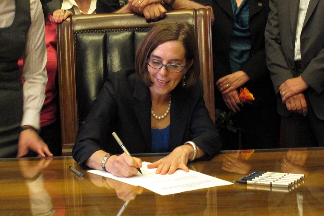 Oregon Gov. Kate Brown (D) signs a bill expanding access to contraception during a ceremony at the state Capitol in Salem, Oregon, on June 11, 2015. (AP/Jonathan J. Cooper)