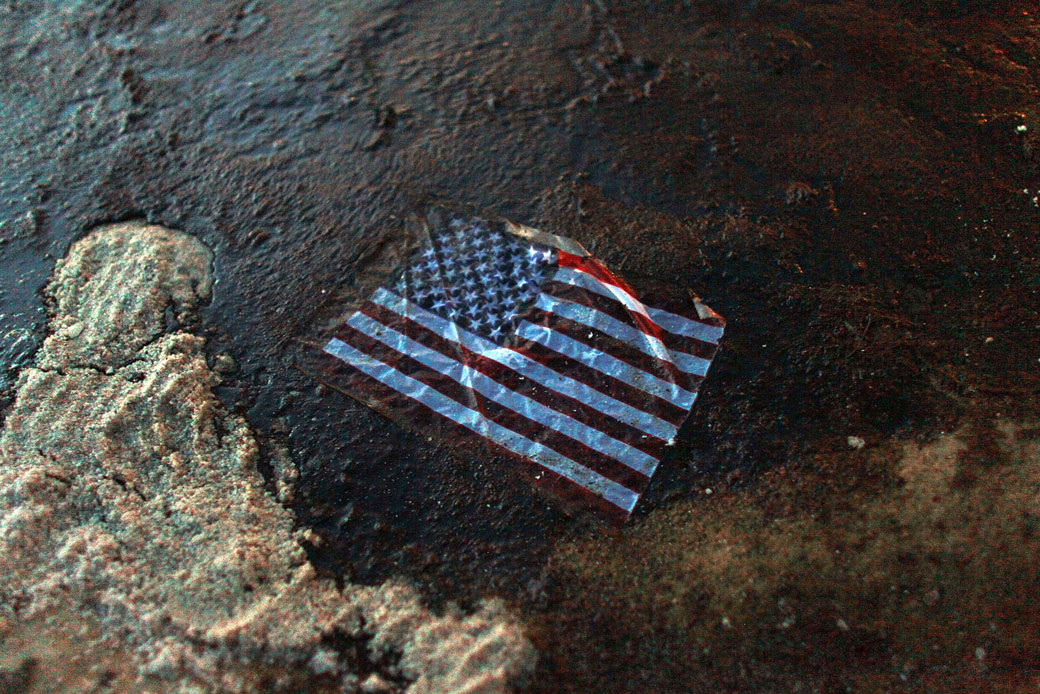 An American flag lies in a slick of oil that washed ashore from the Deepwater Horizon oil spill in the Gulf of Mexico on July 4, 2010, in Gulf Shores, Alabama. (Getty/Joe Raedle)