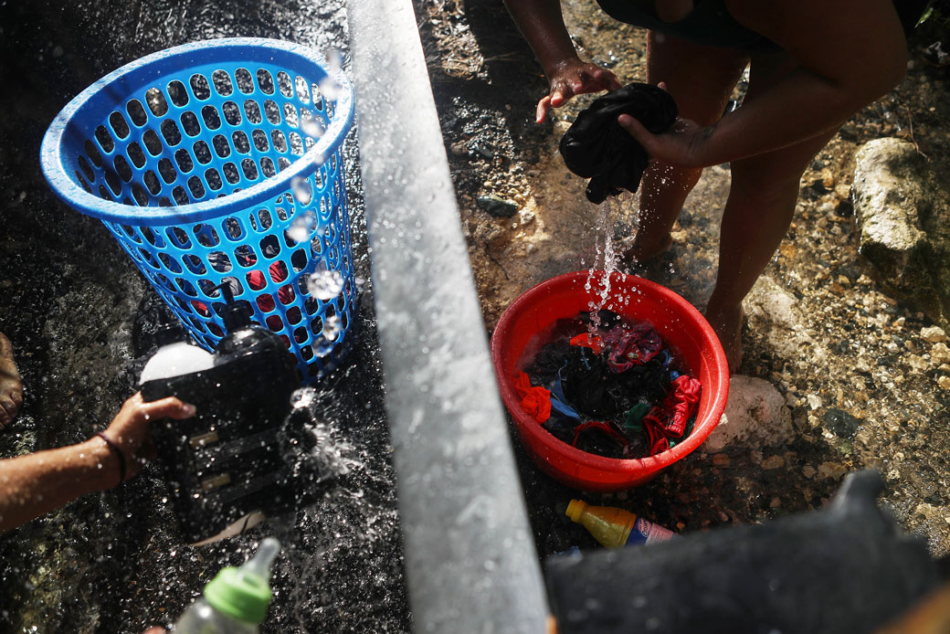A woman washes clothes with water funneled from a stream nearly one month after Hurricane Maria struck in Utuado, Puerto Rico, October 2017. (Getty/Mario Tama)