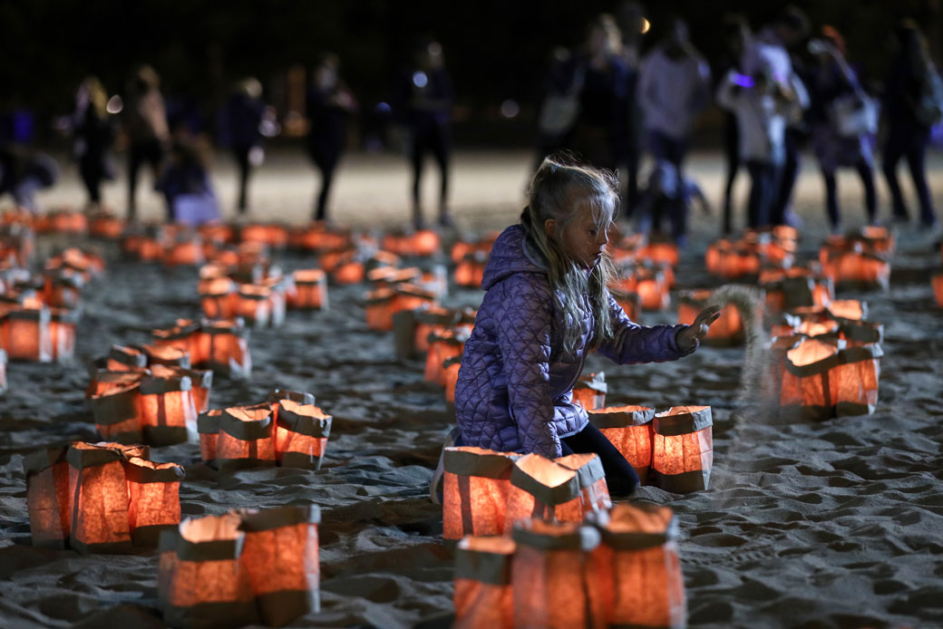 A girl sits among lighted candles during the traditional commemorative ceremony held for domestic violence victims at Chicago's North Avenue Beach, October 2017. (Getty/Bilgin Sasmaz/Anadolu Agency)