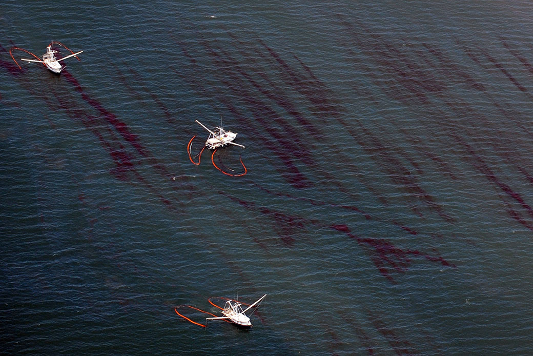 Commercial fishing boats drag booms through an oil slick that passed inside the protective barrier formed by Louisiana’s Chandeleur Islands, during cleanup operations for the BP Deepwater Horizon oil spill, May 7, 2010. (Getty/AFP/Mark Ralston)