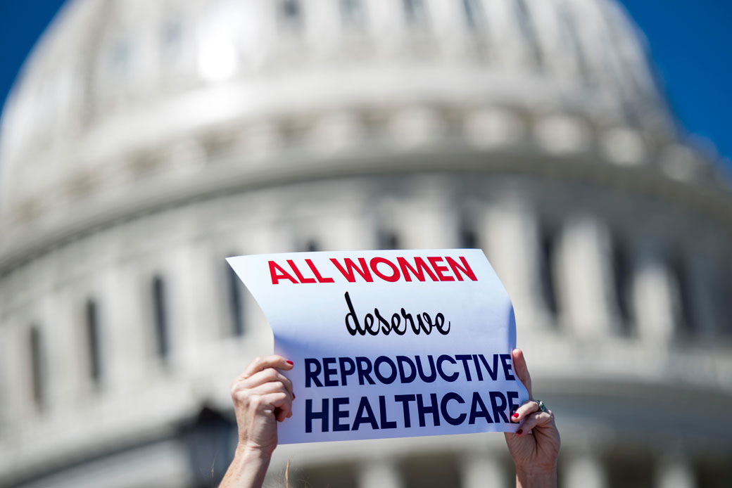 A woman holds a sign in front of the U.S. Capitol on International Women's Day, March 2017. (Getty/Melina Mara)