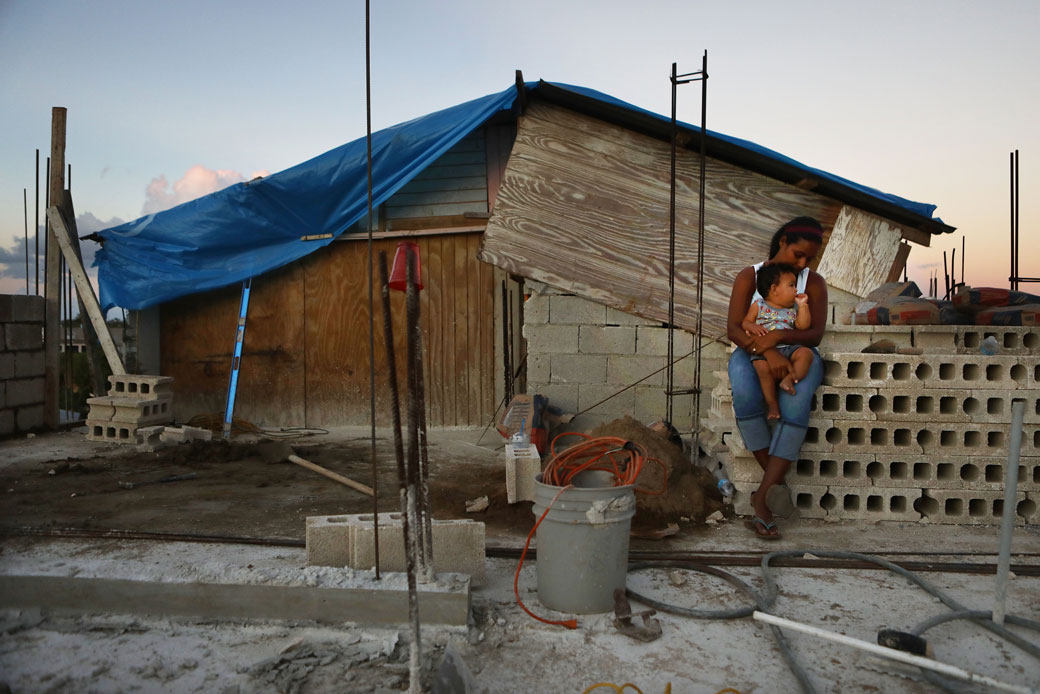 A mother holds her 9-month-old baby at their makeshift home, under reconstruction, after it was mostly destroyed by Hurricane Maria in Puerto Rico, December 2017. (Getty/Mario Tama)