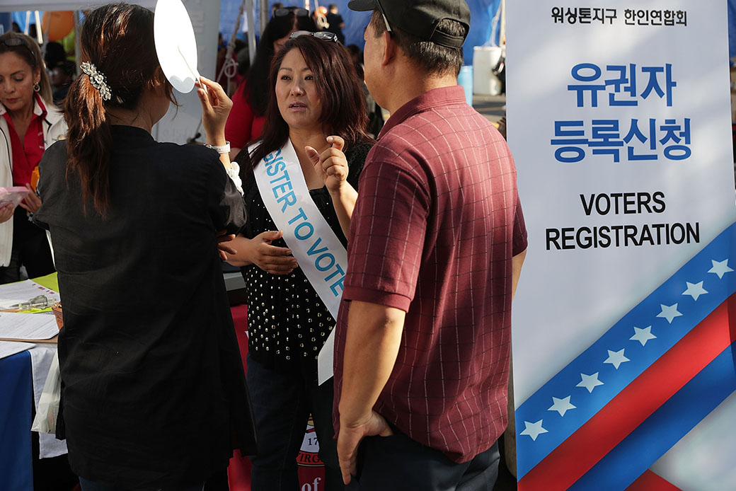 Kelly Lee of the Korean American Association of Washington Metropolitan Area answers questions from a couple as she helps register voters during the annual KORUS festival, a Korean cultural festival, October 2, 2016, in Tysons Corner, Virginia. (Getty/Alex Wong)