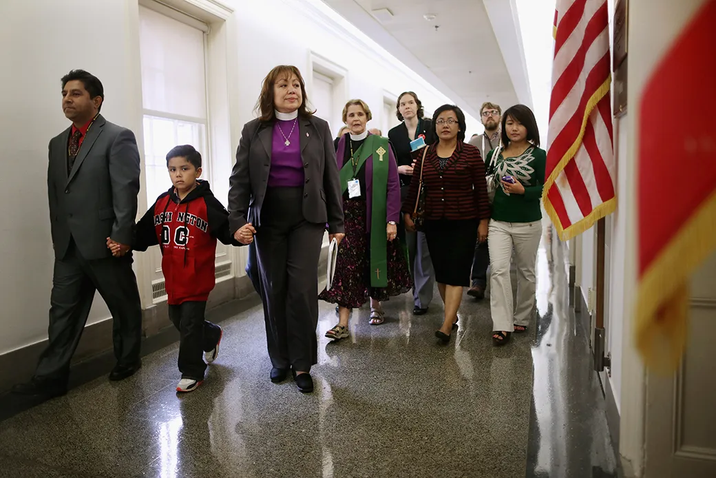 Led by Bishop Minerva Carcaño (third from left), a father and son join people from various Christian denominations at the constituent office of former Speaker of the House John Boehner (R-OH) while lobbying for immigration reform on Capitol Hill, October 8, 2013, in Washington. (Getty/Chip Somodevilla)