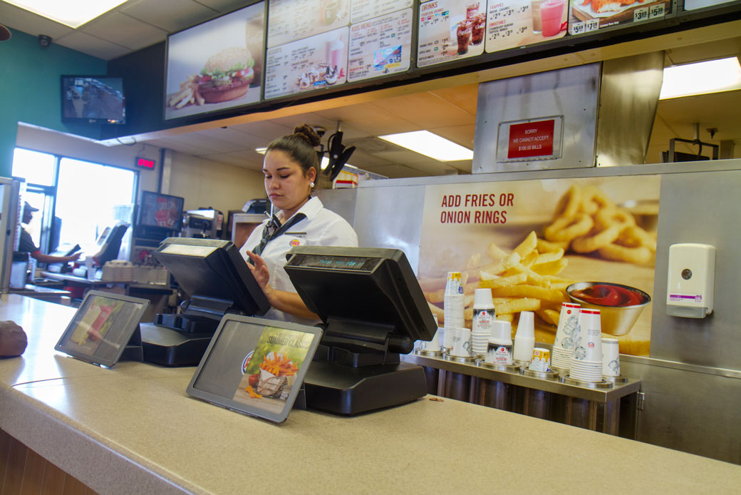A cashier works behind the counter at a fast food restaurant. (Getty/Jeffrey Greenberg)