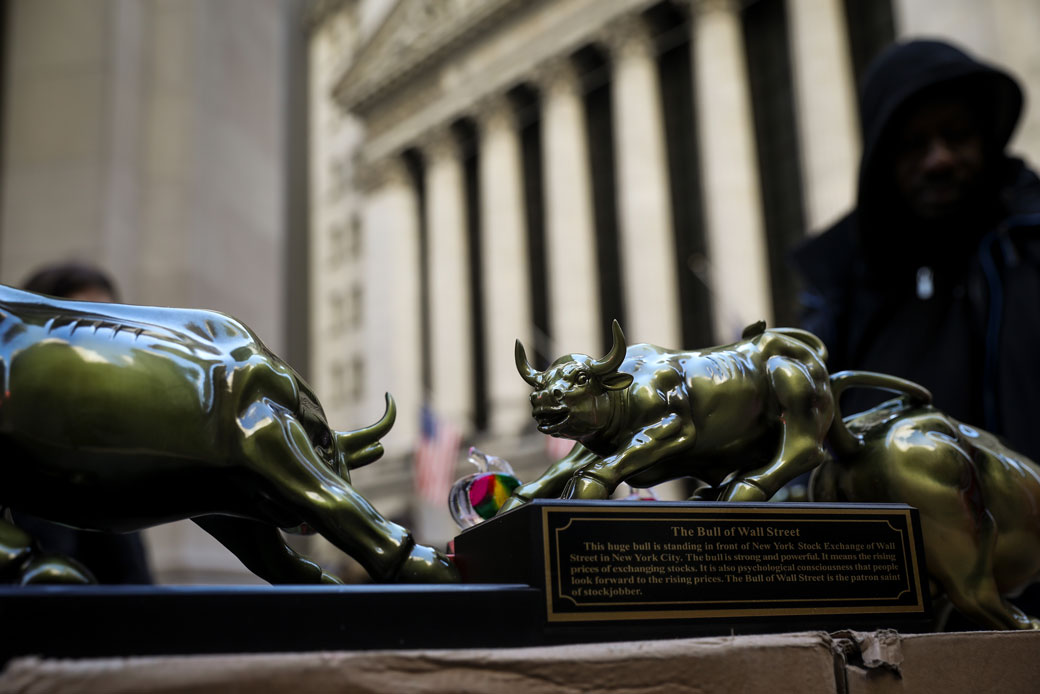 A street vendor sells replicas of the Wall Street Bull statue outside the New York Stock Exchange, March 2018. (Getty/Drew Angerer)