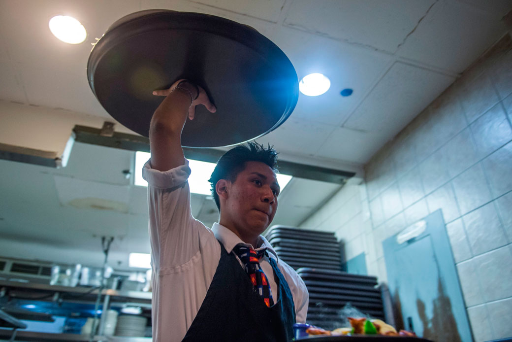 A waiter carries food out of the kitchen of a Washington, D.C., restaurant, January 2018. (Getty/Andrew Caballero-Reynolds)