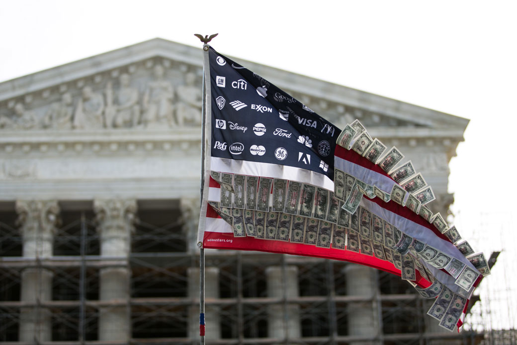 A flag adorned with corporate logos and fake money flies in front of the U.S. Supreme Court in Washington, D.C., October 2013. (Getty/Drew Angerer)