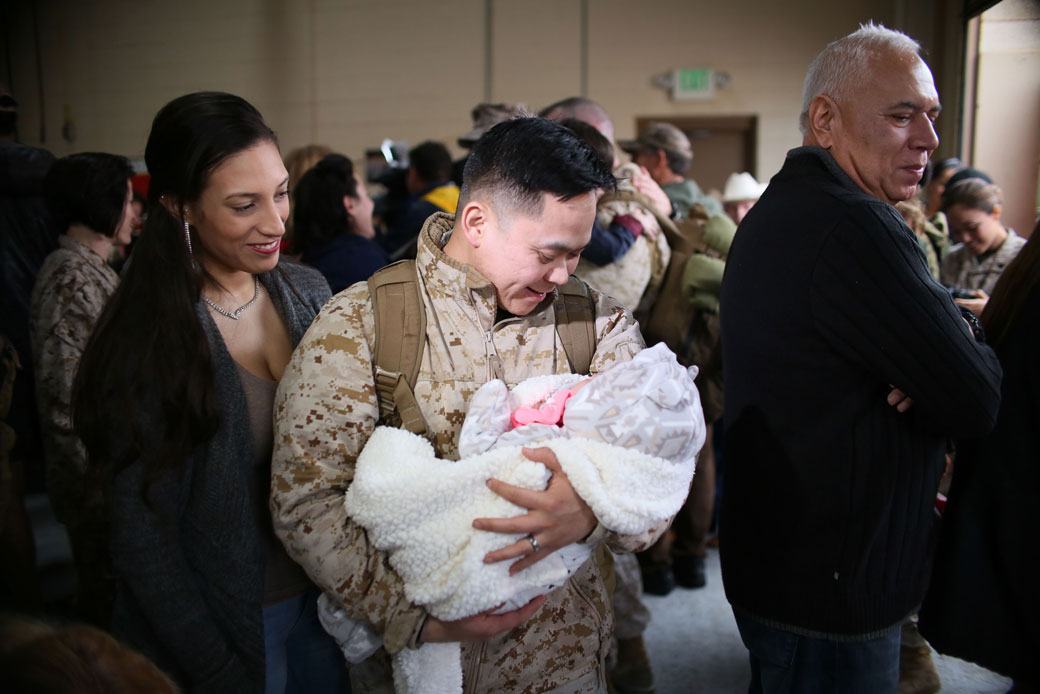 A U.S. Marine looks at his daughter for the first time with his wife during a homecoming at Camp Pendleton in Oceanside, California, December 2016. (Getty/Sandy Huffaker)