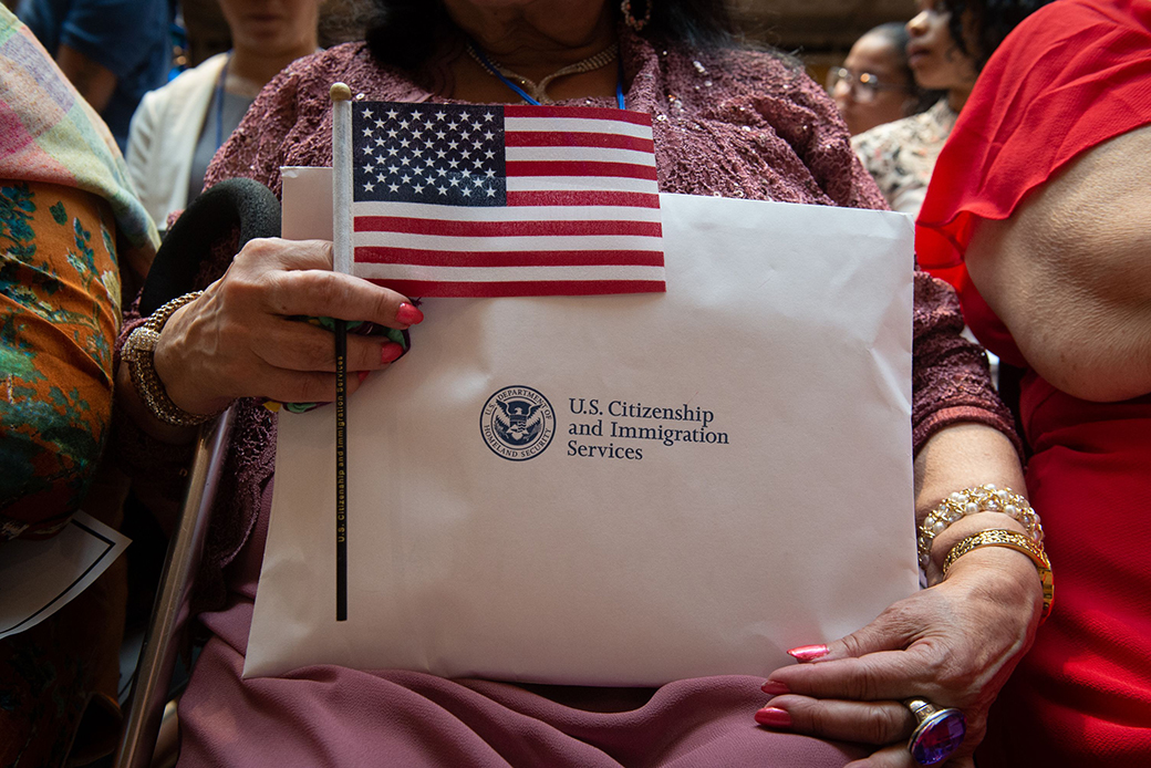 A woman holds the flag and her paperwork as the US Citizenship and Immigration Services welcomes 200 new citizens from 50 countries during a ceremony in honor of Independence Day at the New York Public Library on July 3, 2018 in New York. (Photo by Bryan R. Smith / AFP)        (Photo credit should read BRYAN R. SMITH/AFP/Getty Images)