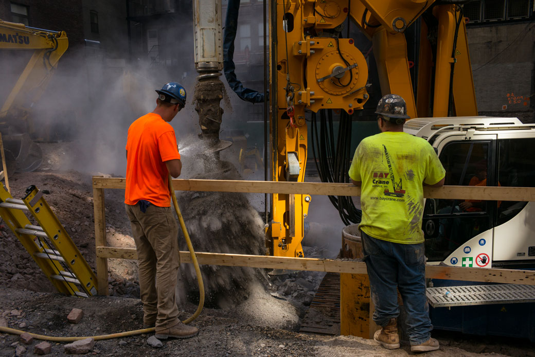 Construction workers clean a rotary drilling auger at a building site in New York City, July 2018. (Getty/Robert Nickelsberg)