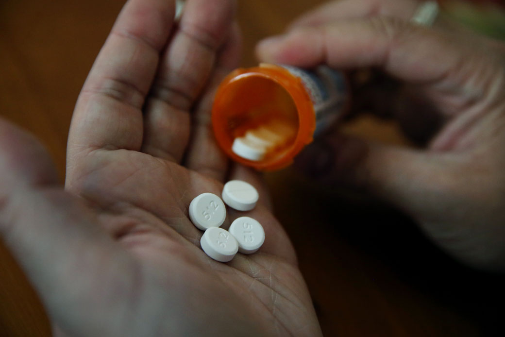 A patient removes several pills from her prescription bottle, June 2016. (Getty/The Boston Globe/Craig F. Walker)