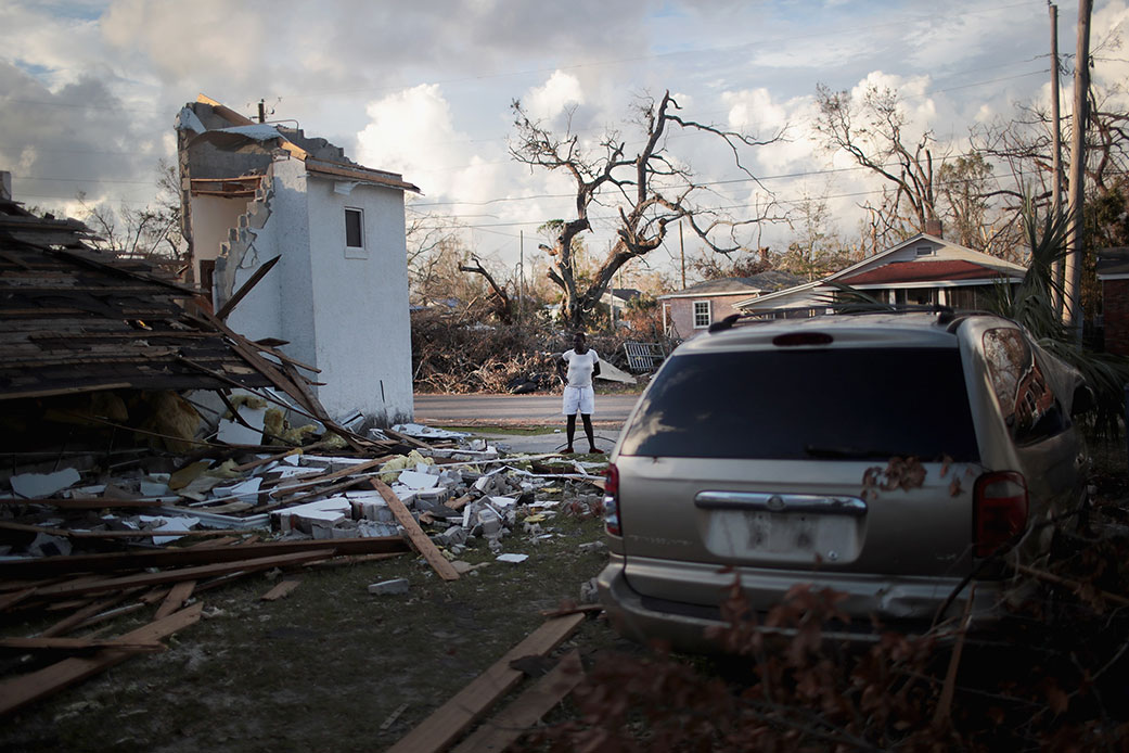A woman stands between her home and the church next door, both of which were severely damaged by Hurricane Michael on October 20, 2018, in Panama City, Florida. (Getty/Scott Olson)