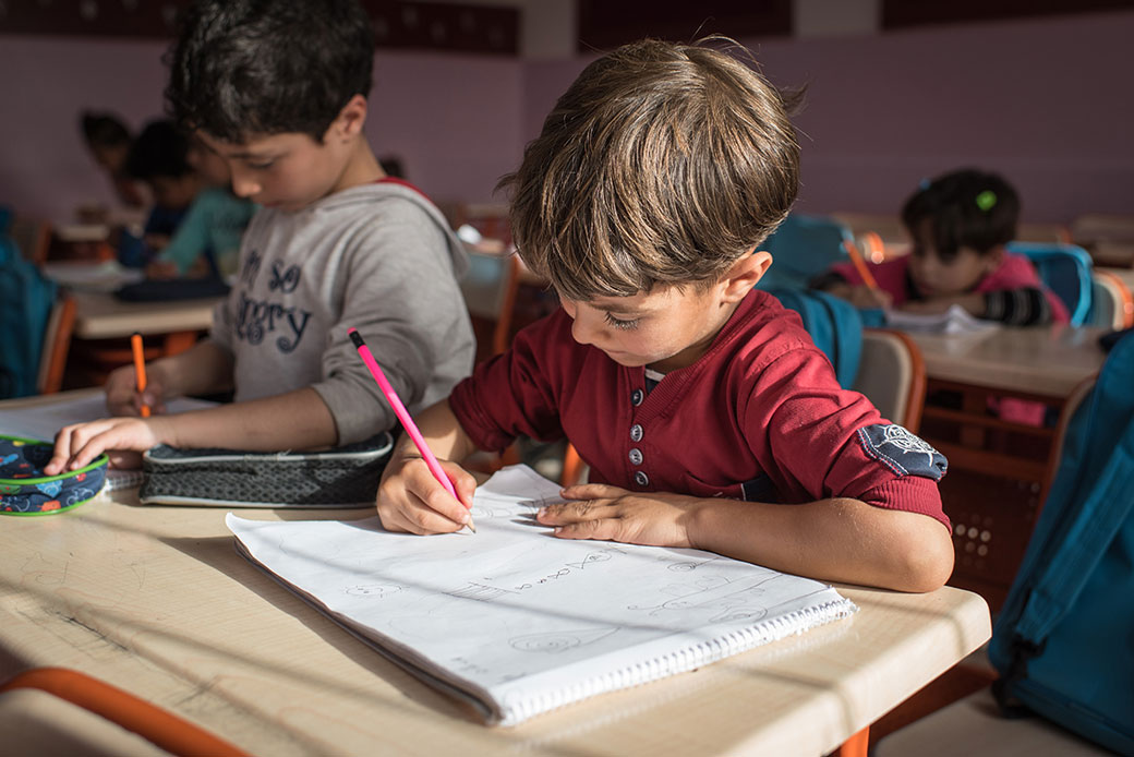 Syrian refugee children draw in their notebooks in a refugee camp in Turkey, August 2017. (Getty/Diego Cupolo)
