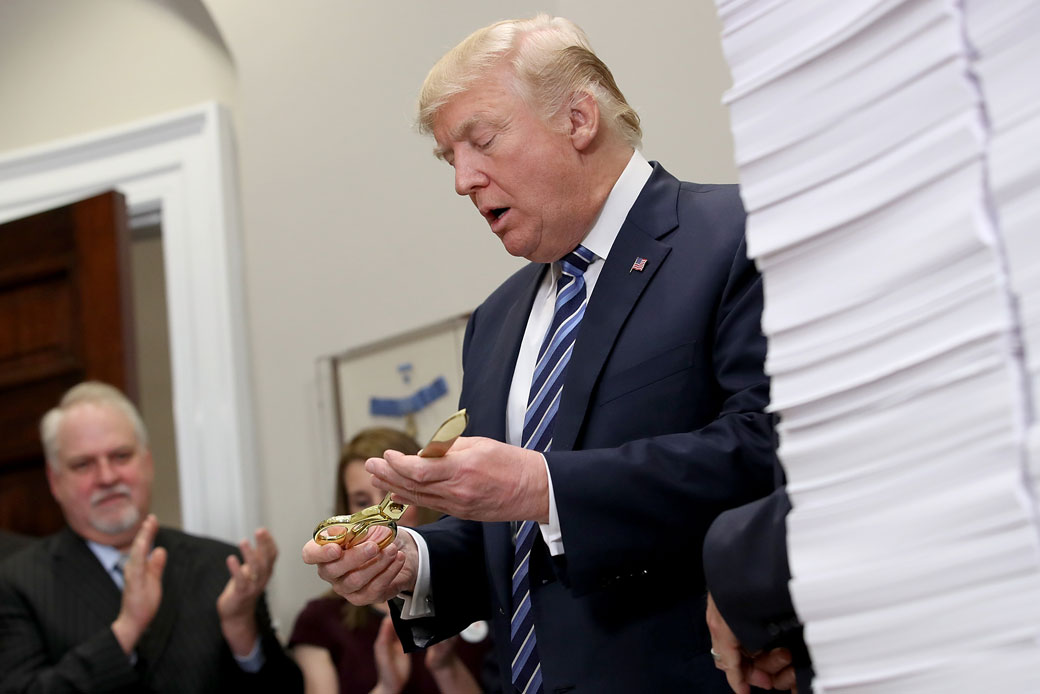 President Donald Trump holds a pair of gold scissors during an event at the White House promoting the administration's efforts to decrease federal regulations, December 2017. (Getty/Win McNamee)