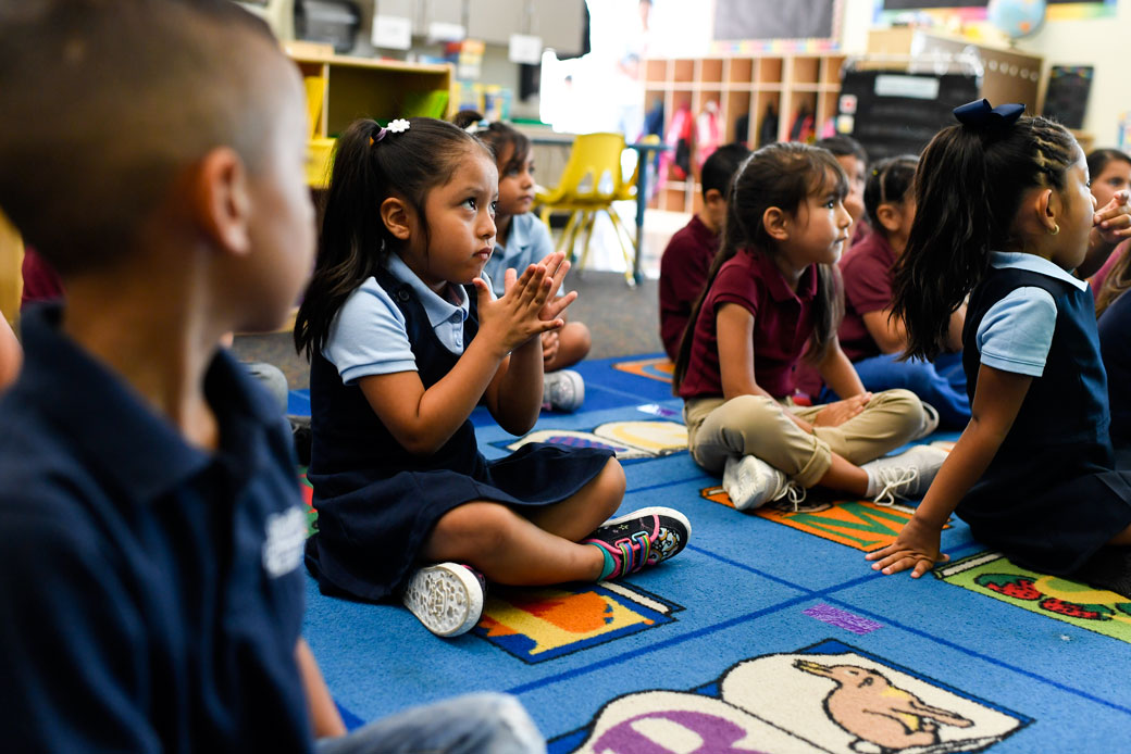 Kindergarten students in Denver participate in an activity during the first day of school, August 2018. (Students sitting on rug; student claps as kindergarten students participate in an activity during first day of school)