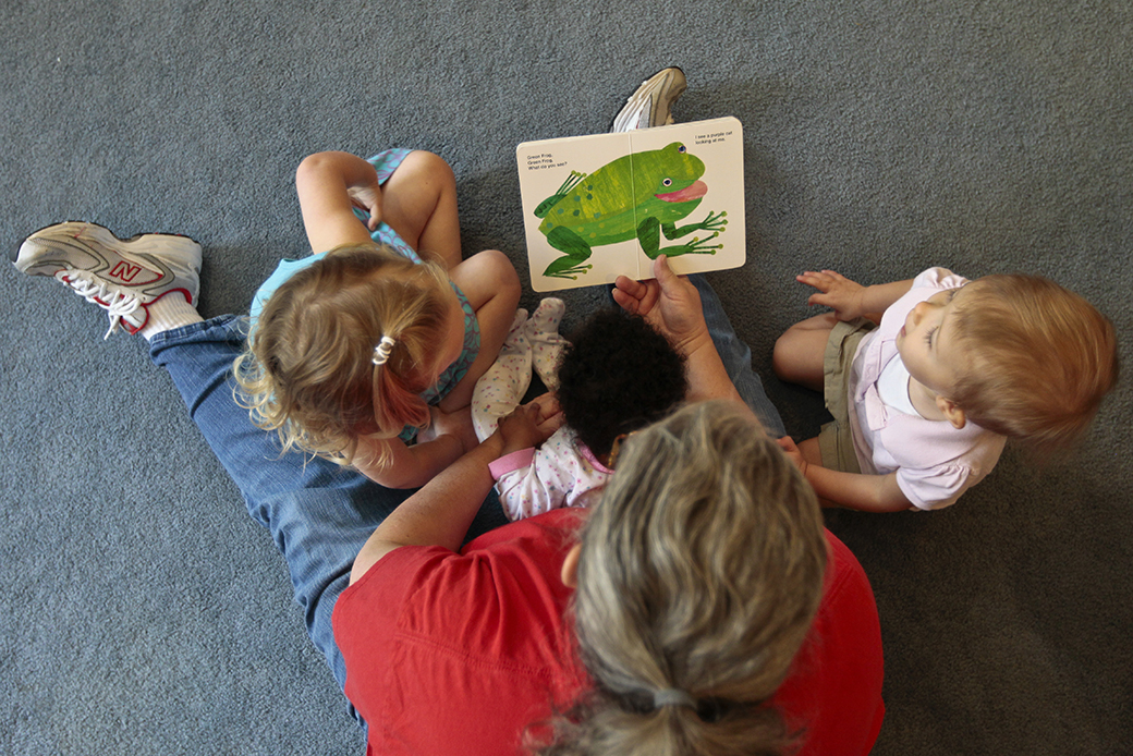 A woman reads to children as she runs her at-home day care in Virginia, July 2012. (Getty/Jabin Botsford)