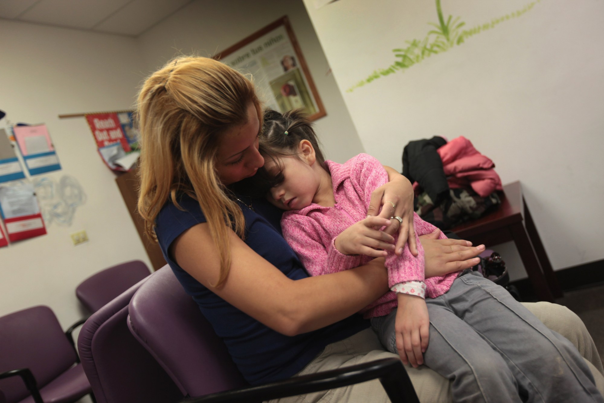 AURORA, CO - JULY 28:  Jessica Mejia holds her sick daughter Joselyn in the waiting room at a low-cost clinic run by the Rocky Mountain Youth Clinics in Aurora, Colorado. (Photo by John Moore/Getty Images)