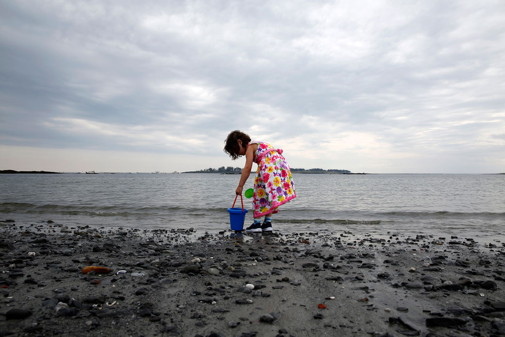 A 4-year-old girl gathers sand and seawater at Crescent Beach State Park in Cape Elizabeth, Maine, June 2018. (Getty/Portland Press Herald)