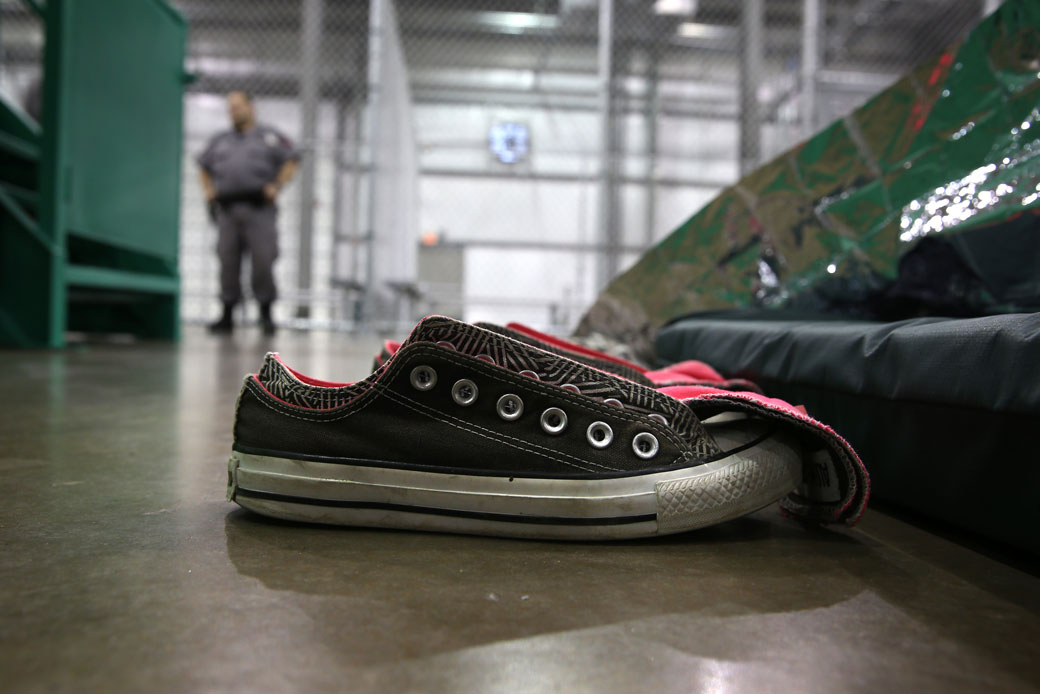 A security guard watches as migrant girls sleep at a U.S. Border Patrol detention facility in McAllen, Texas, September 2014. (Getty/John Moore)