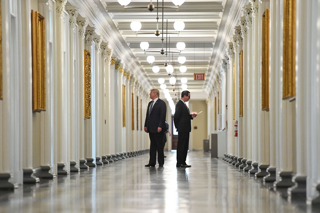  (President Donald Trump looks at portraits on the wall as he walks down a corridor with Treasury Secretary Steven Mnuchin at the Treasury Building on April 21, 2017, in Washington, D.C.)