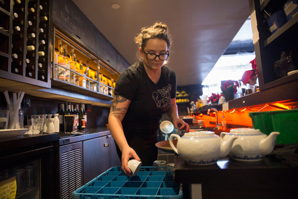  (A woman who works as a bartender in a restaurant in Maine puts away dishes.)