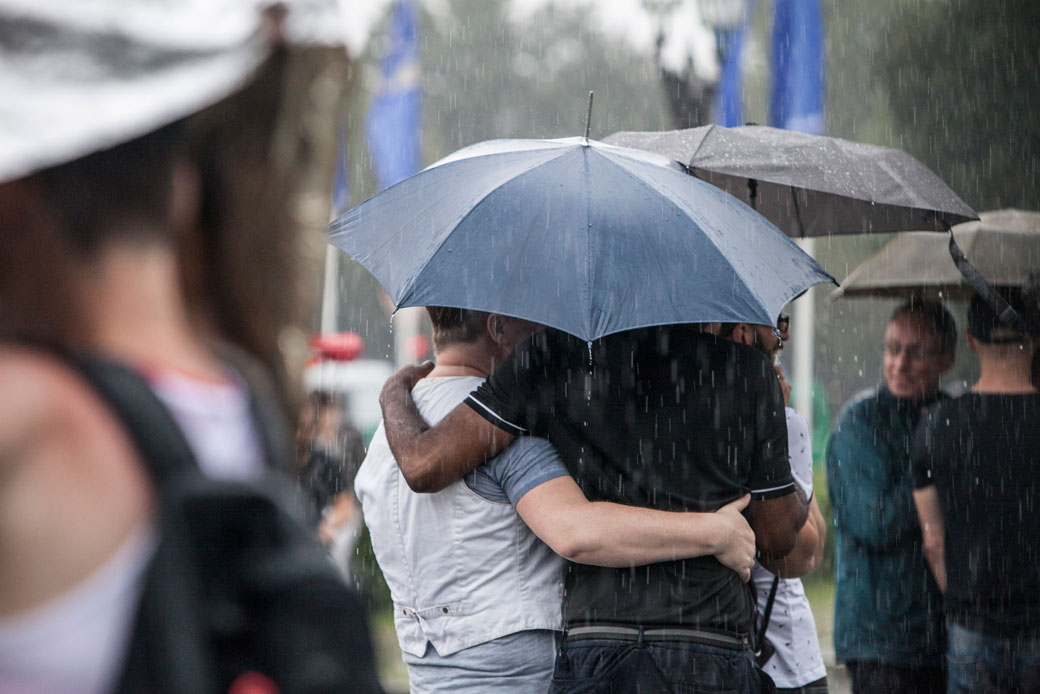  (People hide under umbrellas from heavy rain during a pride parade.)