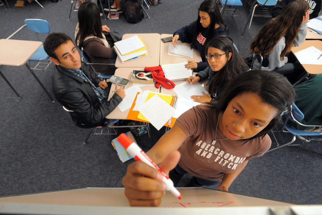 A student at a Redondo Beach, California, high school writes a math problem on the classroom's whiteboard as her peer group and tutor look on, March 2011. (Getty/Digital First Media/Torrance Daily Breeze/Scott Varley)