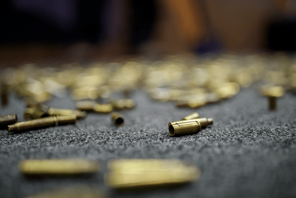 (Expended ammunition casings are shown on a gray surface.)