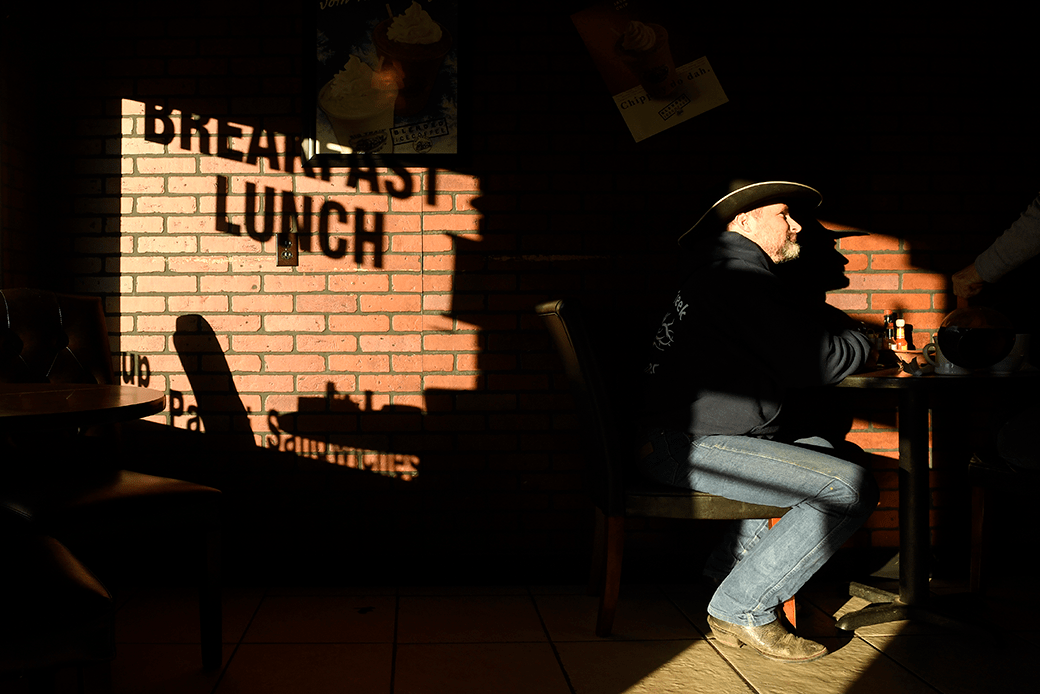 (A man is shown drinking coffee and having breakfast in a small-town cafe.)