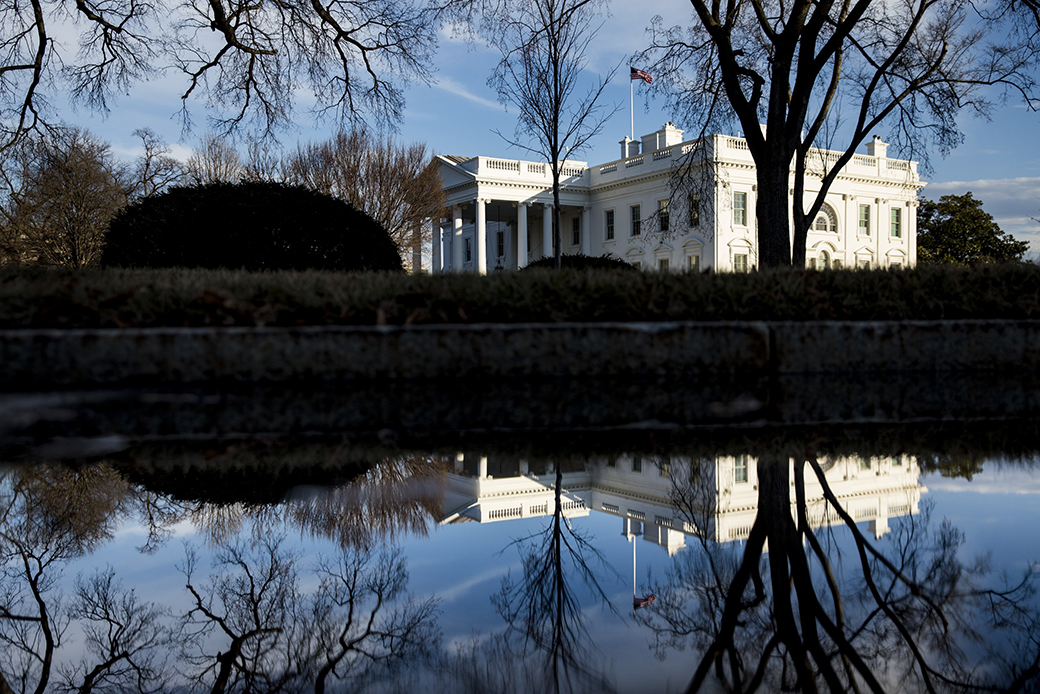 The White House is reflected in a rain puddle after a press briefing at the White House in Washington, February 2018. (The White House reflected in a rain puddle.)