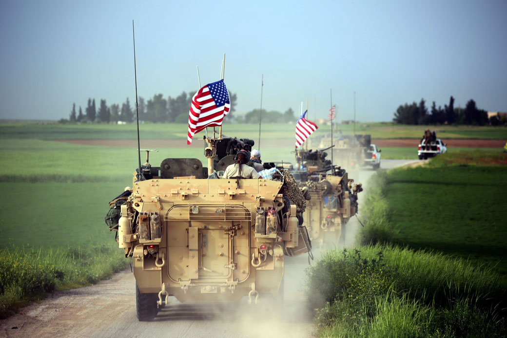 U.S. forces, accompanied by Kurdish YPG fighters, drive armored vehicles near the northern Syrian village of Darbasiyah in April 2017. (Vehicles drive near Syrian village.)