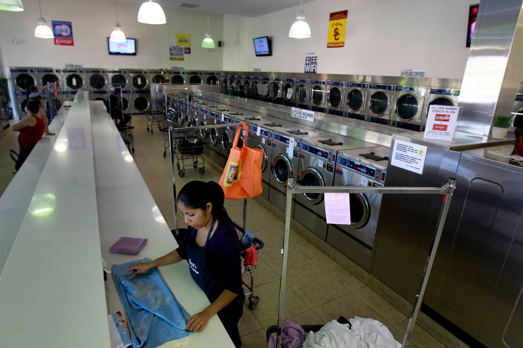 A woman folds laundry for a client at a laundromat in Los Angeles, October 2014. (Getty/Allen J. Schaben/Los Angeles Times)
